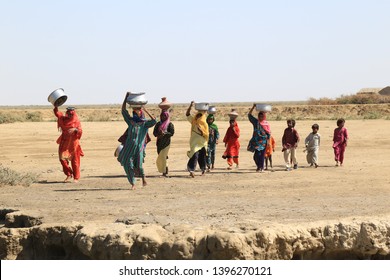 Tharparkar Sindh, Pakistan - March, 2019: Children wearing colorful dress coming to watering in the pot or filling water pots from stagnant water pond in Thar Pakistan, the area struck by drought