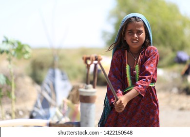 Tharparkar Sindh, Pakistan - March, 2019: Woman Girl Wearing Colorful Clothes Filling Water From Hand Pump In Water Pots In Thar Pakistan, It Is The Desert Area Most Affected By Drought In Pakistan 