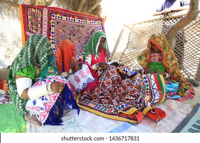 Tharparkar Sindh, Pakistan - March, 2019: Thar Woman Sewing Traditional Bed Sheets In Colourful Dress Sitting On Ground Inside Their Rural House, Women Smiling Happy Faces Rajhastan Desert