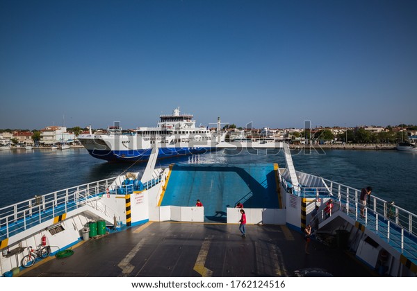Thassos / Greece - 10.28.2015: People on a ferry\
boat\'s deck and a passenger ship moored to the harbour, Thassos\
Island, Greece