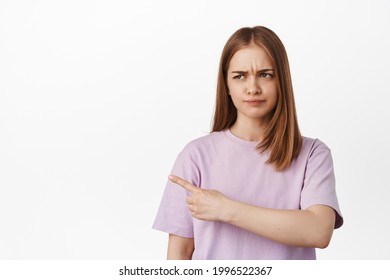 That It Bad. Displeased Blond Woman Pointing, Furrow Eyebrows With Dislike, Staring At Smth With Judging Face, Showing Awful Banner Logo On Left Side, Complaining, White Background