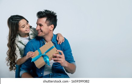 Is That For Me?! Close-up Photo Of A Happy Father In Denim Outfit Smiling While Receiving A Present From His Beloved Child, Who Is Looking Tenderly Into His Eyes.