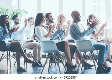That was really great seminar. Side view of group of young cheerful people sitting on conference together and applauding  - Shutterstock ID 439232554
