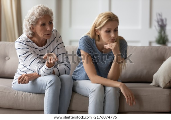 That is your fault. Unhappy sad young woman child,\
grandkid, daughter in law sitting on sofa getting distracted from\
angry scolding mum, grandma or mother in law avoiding conflict,\
taking her mind off
