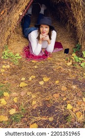 Thatched Hut In The Autumn Forest. Cabin In The Countryside. Happy Woman Is Resting In Nature. Escape From The Bustle Of The City To Nature.