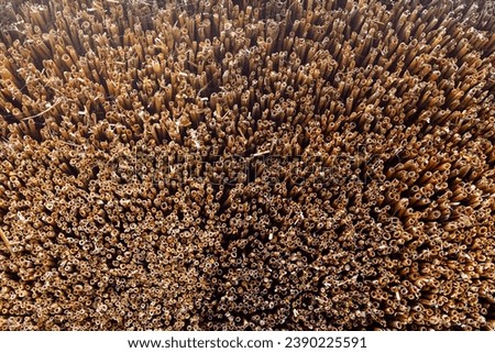 The thatched roof texture of an old house..Old straw as a material for the roof. Close up of straw roof, brown background.