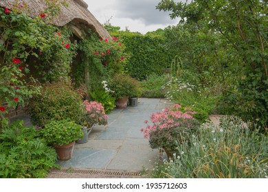 Thatched Roofed Cottage, With Flagstone Pathway And Traditional Cottage Garden