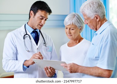 Thats Completely Within Normal Range. Shot Of A Handsome Young Doctor Explaining Results To A Senior Couple.