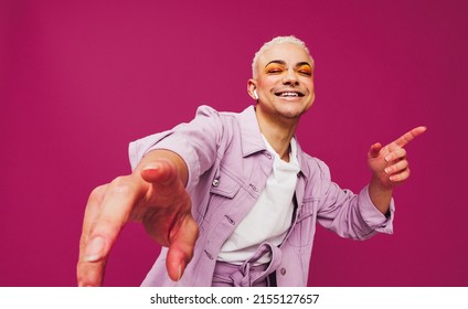 That's my favorite song. Happy young man dancing to his favorite music while wearing wireless earphones. man smiling cheerfully while standing against a purple background. - Shutterstock ID 2155127657