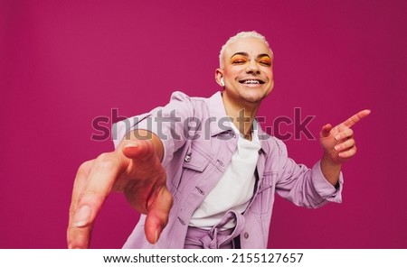 That's my favorite song. Happy young man dancing to his favorite music while wearing wireless earphones. man smiling cheerfully while standing against a purple background.