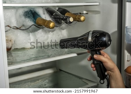 Thawing ice from a fridge with the help of a hair dryer. Stock photo © 