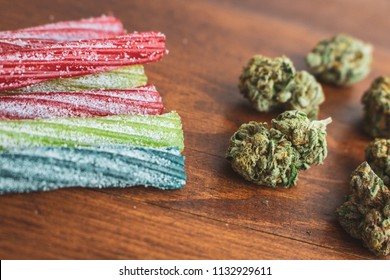 THC / CBD Infused Sour Candy Straws And Marijuana Buds On Wood Background