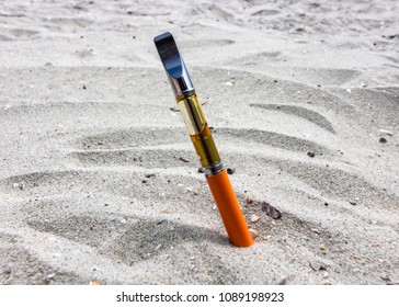 THC Oil Vape Pen In The Sand At The Beach