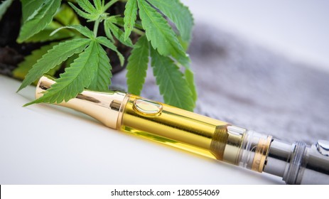 THC/CBD Cannabis Oil & Terpenes Filled Cartridges Up Close With Marijuana Plant Leafs