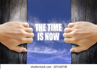 "The time is now" text in the sky behind 2 hands opening the wooden door.