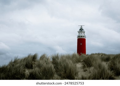 Thea Lighthouse on the northernmost top of the Dutch island of Texel, Red lighthouse tower on the sand dunes with european marram grass and cloudy sky and dark tone, North Holland, Netherlands - Powered by Shutterstock