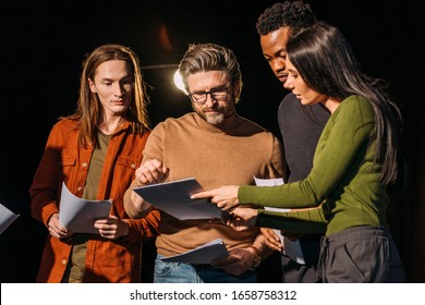 theater director, multicultural actors and actress rehearsing with scripts on stage - Shutterstock ID 1658758312