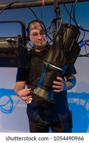 Theater Lighting Technician Adjusting Focus Of Lighting Elements Backstage Next To A Let Cyclorama Curtain.