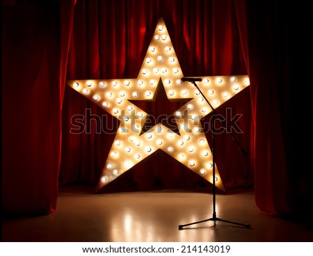 Theater stage with red curtains,microphone  and golden lightstar on background