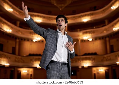 Theatre play a young actor in original image. Sincere emotions transmitted camera. Photo for cultural and fashion magazines, posters and websites. Brunette male in gray suit singing, gesturing - Shutterstock ID 2248668633