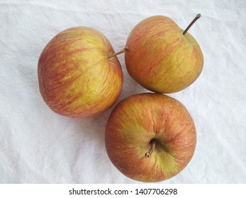 Thee red apples on a while sheet