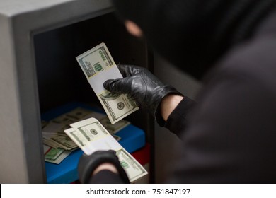 theft, burglary and people concept - thief stealing money from safe at crime scene