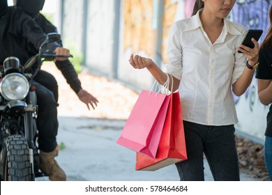 A Theft Riding Motorcycle And Trying To Steal Bag From Woman While Walking Along Street And Using Mobile Phone.