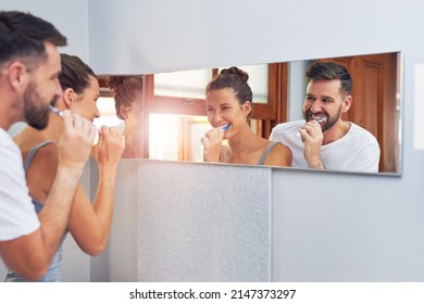 Their Daily Early Morning Routine. Shot Of A Young Couple Brushing Their Teeth Together At Home.