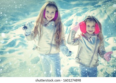 Theme Christmas holidays winter new year. Portrait of two little girls play with snow in winter. Children in Winter Park playing snowballs