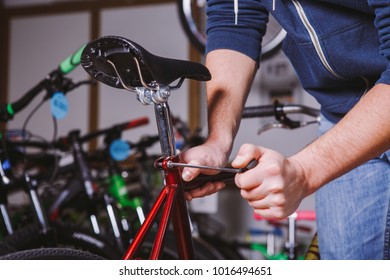 Theme repair bikes. Close-up of a Caucasian man's hand use a hand tool Hex keys to adjust and install the silver color Seat Posts on a red bicycle. - Powered by Shutterstock