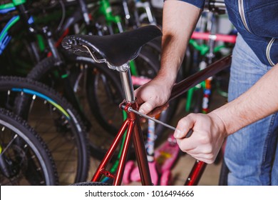 Theme repair bikes. Close-up of a Caucasian man's hand use a hand tool Hex keys to adjust and install the silver color Seat Posts on a red bicycle. - Powered by Shutterstock