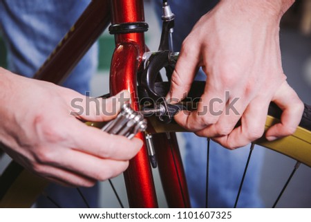 Theme repair bikes. Close-up of a Caucasian man's hand use a hand tool hexagon set to adjust and install Rim Brakes on a red bicycle.