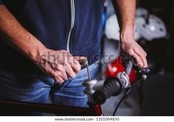 Theme repair bikes. Close-up of a Caucasian man\'s\
hand use a hand tool Hex key to install Stems a bicycle handlebar\
mount for a racing bike