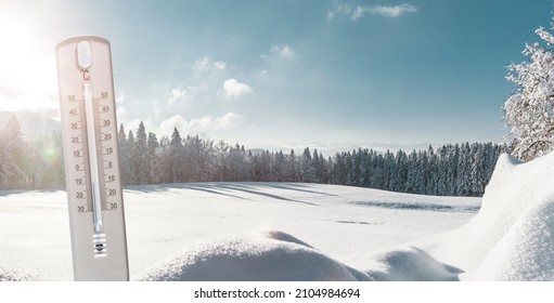 Themometer with minus temperatures in Celsius in front of a winter landscape