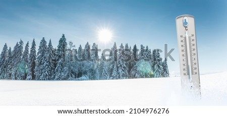 Themometer with minus temperatures in Celsius in front of a winter landscape