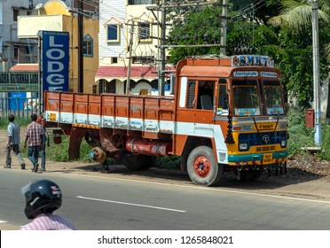 THENI, TAMIL NADU, INDIA - OCTOBER 28, 2018: A Tata Truck, With Its Rear Wheel Missing, Stands Jacked Up, By The Roadside Near To A Small Tyre Repair Facility Where The Wheel Is Being Fixed.    