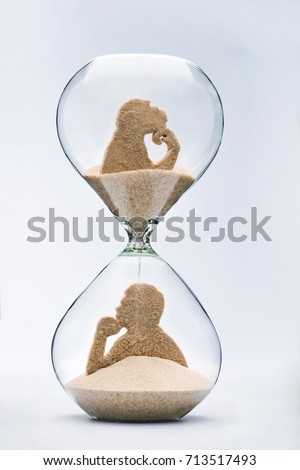 Theory of evolution concept, with falling sand taking the shape of a monkey and a man inside a hourglass