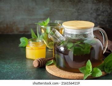 Therapeutic herbal green tea. Hot tea with honey mints in a glass teapot on a stone table. Copy space. - Shutterstock ID 2161564119