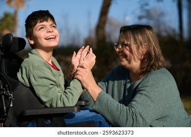 Therapist assisting child with disability in wheelchair outdoors - cerebral palsy concept