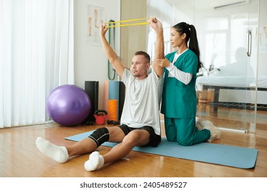 Therapist controlling patient keeping arms straight when exercising with resistance band - Powered by Shutterstock