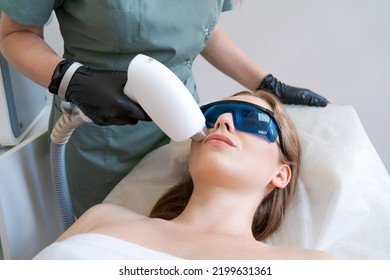 Therapist Cosmetologist Undergoes Laser Treatment On Face Young Woman In Beauty Clinic. Facial Laser Hair. Epilation Procedures. Satisfied Customer, Selective Focus.