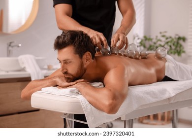 Therapist giving cupping treatment to patient on massage couch in spa salon