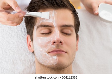 Therapist Hands With Brush Applying Face Mask To A Young Man In A Spa