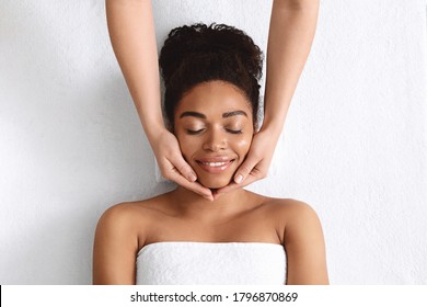 Therapist Making Lifting Facial Massage For Beautiful Smiling Black Lady, Top View