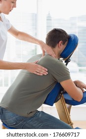 Therapist Massaging Man On Massage Chair In Hospital