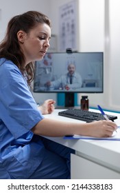 Therapist Nurse Discussing Sickness Diagnostic With Remote Doctor During Online Videocall Meeting Conference During Clinical Consultation In Hospital Office. Telemedicine Call On Computer Screen