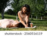 Therapist performing reiki healing treatment on a patient lying on a blanket on the grass in a park