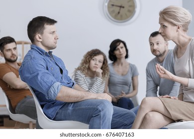 Therapist speaking to a man during group counseling session