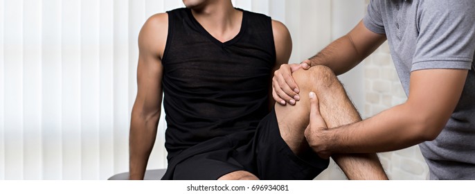 Therapist treating injured knee of athlete male patient in clinic - sport physical therapy concept,panoramic banner