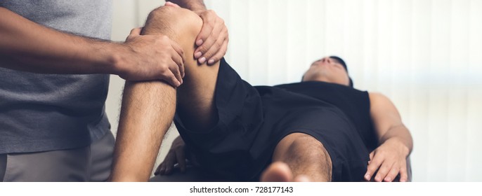 Therapist treating injured knee of athlete male patient - sport physical therapy concept, panoramic banner